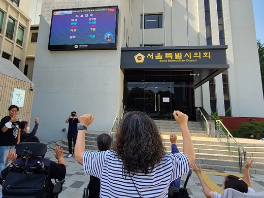 21일 오후 3시 30분경, 서울시의회 본회의에서 ‘서울시 장애인 탈시설 및 지역사회 정착 지원에 관한 조례’가 가결되자 장애인단체 활동가들이 환호하고 있다.ⓒ에이블뉴스